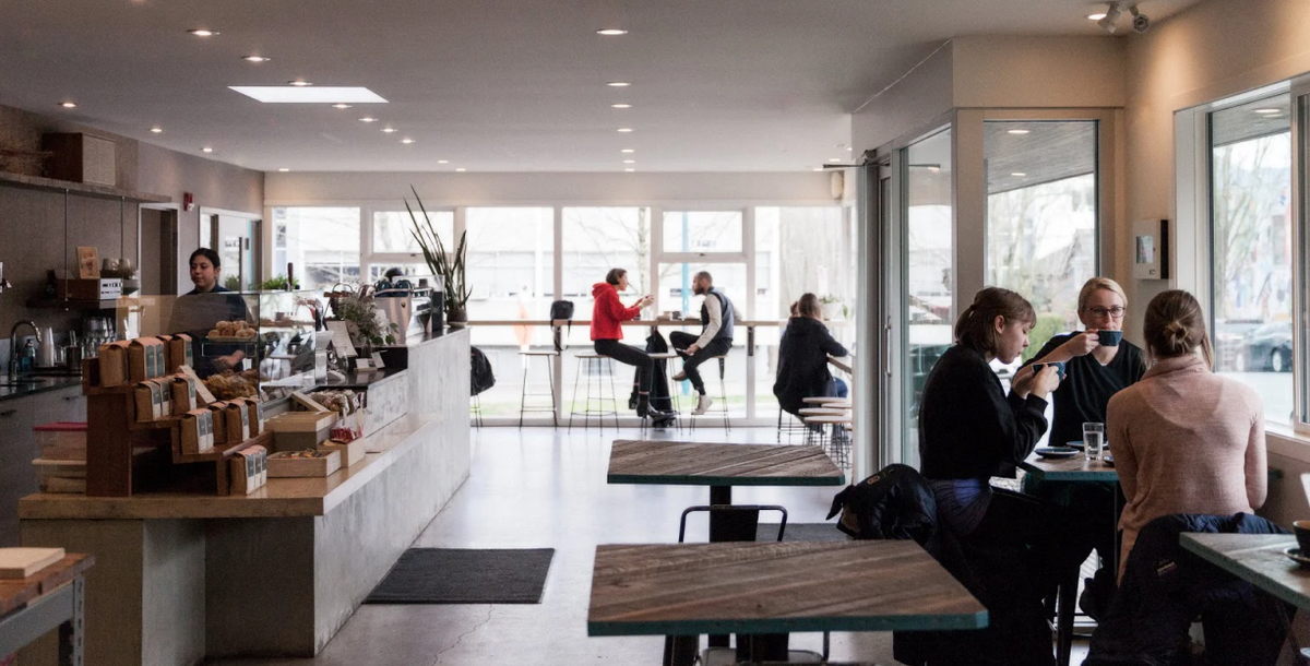 Inside the Elysian cafe and roastery at 7th & Ontario, with people at tables by tall windows