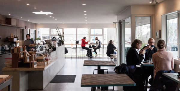 Inside the Elysian cafe and roastery at 7th & Ontario, with people at tables by tall windows