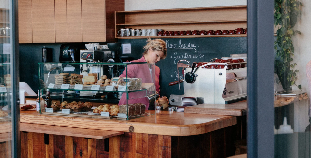 A barista behind the wooden counter at the Elysian cafe at 5th & Burrard